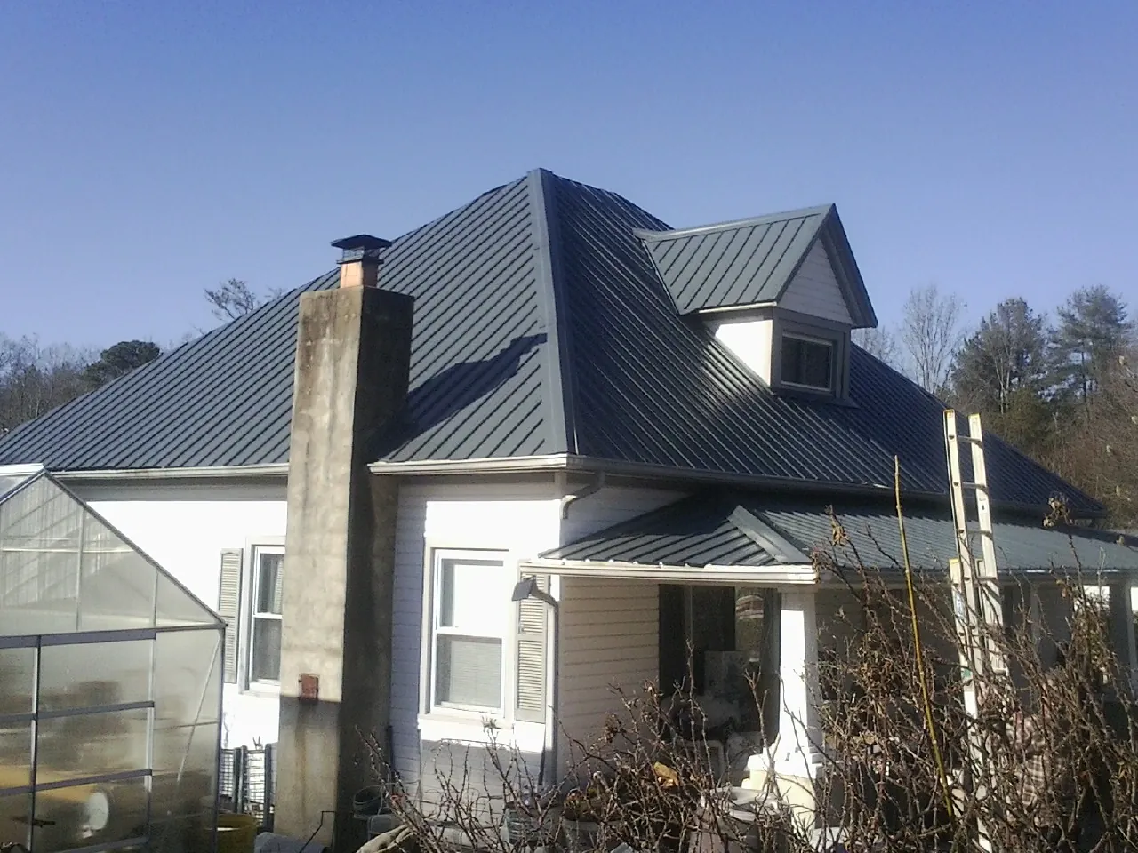 Dark blue standing seam metal roof on a white farmhouse with dormer — Slate & Tile Roof Repair by Roofing Brothers in Allerton