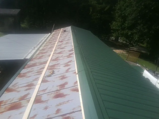 Old rusted panels beside newly installed green metal roofing — Wind Damage Roof Repair by Roofing Brothers in Allerton