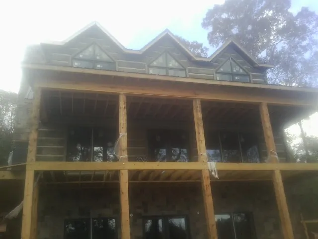 Dormers and porch framing on a large log home under construction — Roof Coating work by our crew in Allerton