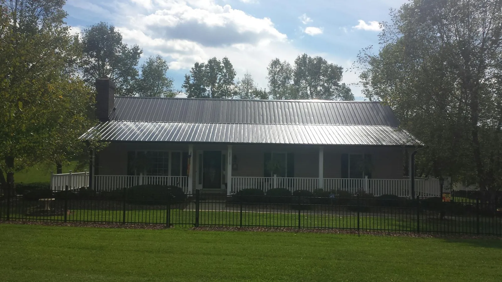 Gray metal roof on a brick ranch with a full width front porch — Gutter Guard Installation work by our crew in Allerton