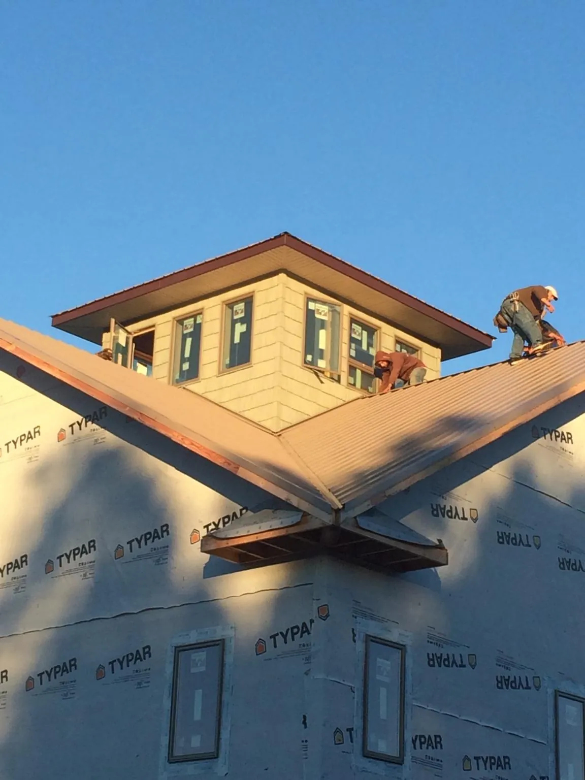 Roofers working around a rooftop cupola on a new metal roof at sunset — Roof Waterproofing in Allerton by Roofing Brothers